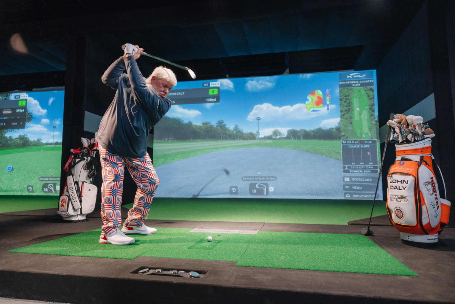 Golfer swinging in an X-Golf indoor simulator bay